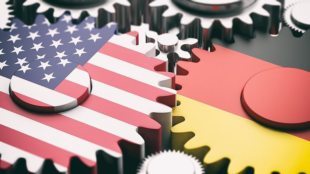 Symbolbild Zusammenarbeit - Zahnräder mit US Flagge und deutscher Flagge