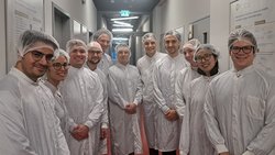 Gruppenfoto der Finalistinnen und Finalistinnen mir Kittel und Haarschutz bei einer Laborführung